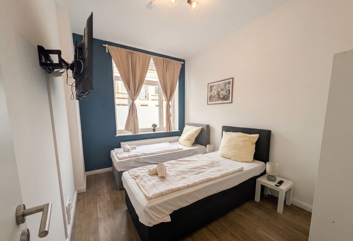 Helles Schlafzimmer mit zwei Einzelbetten und Smart-TV